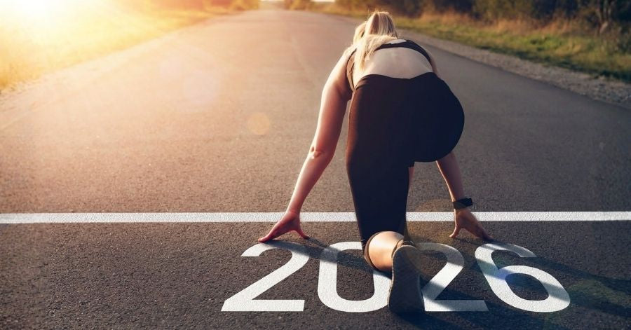 Frau steht am Start einer Laufbahn mit „2026“ Motivationsbild zum Jahresstart – Frau bereitet sich mit Trainingsplan 2026 auf ihre sportlichen Vorsätze vor.