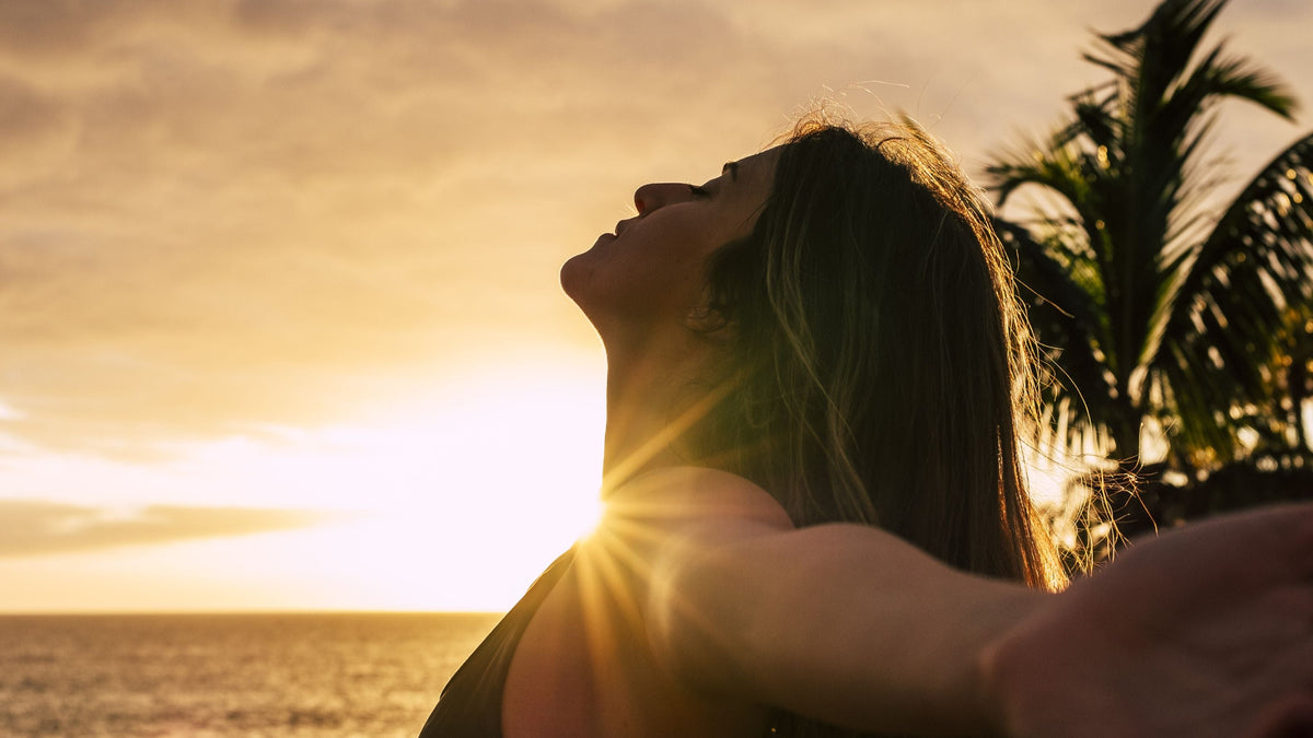 Frau genießt Sonnenlicht am Meer – natürliche Vitamin D Synthese durch UVB-Strahlung